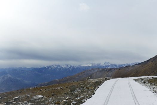 Snow-covered road on a mountain pass in the background