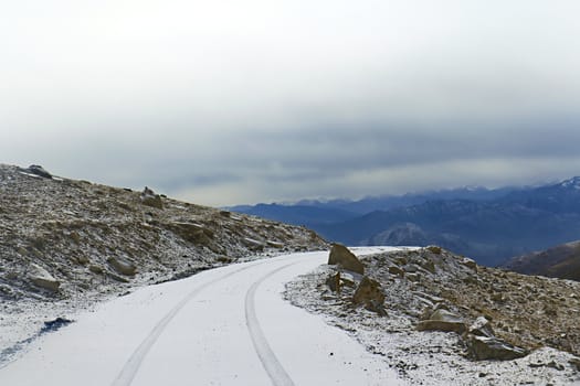 Snow-covered road on a mountain pass in the background