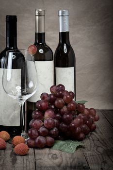 red grapes with wine bottles on wooden background