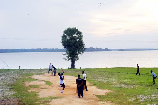 Arugam Bay, Sri Lanka - February 14, 2011: Group of locals are playing cricket. The cricket is the most popular game in Sri Lanka, India and Pakistan. People play it everywhere, yard, street and play ground.