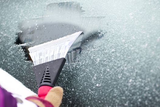 scraping snow and ice from the car windscreen