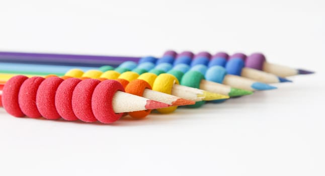 pencils arranged in color order of the rainbow on white background