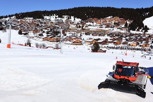 snowplow on ski track in french alpine mountain