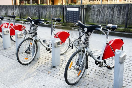 Alternative transportation: Bicycles for rent parked at a station in front of concrete wall in old european city.