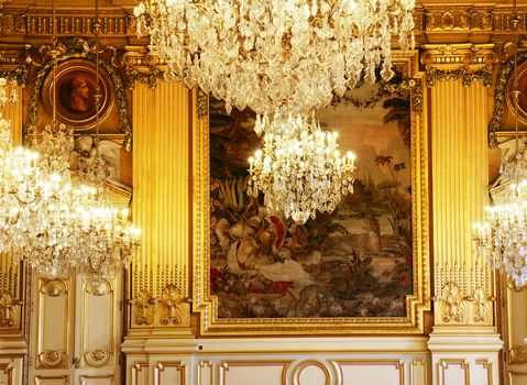 Magnificent, rich and luxurious room of a historic building with gold guilded sculptures, frames, columns and ceilings and beautiful crystal chandeliers, Lyon, France.