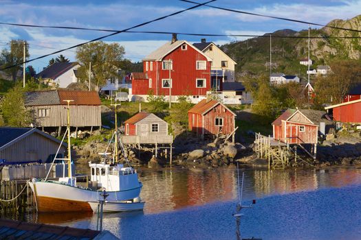 Red fishing rorbu huts and fishing boat in town of Reine on Lofoten islands