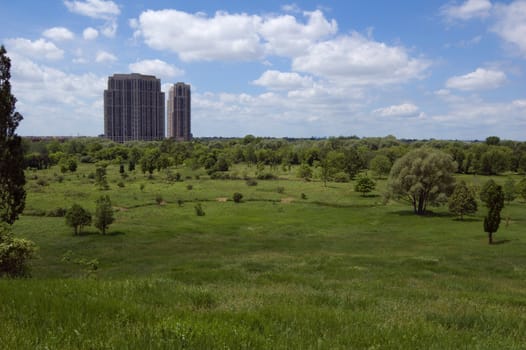 Two big and high buildings above green grass valley