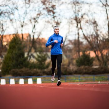 Young woman running at a track and field stadium