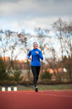 Young woman running at a track and field stadium