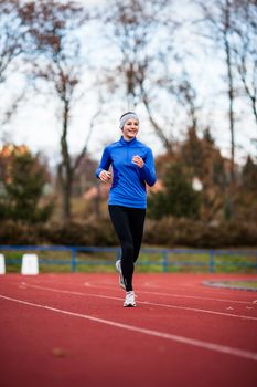 Young woman running at a track and field stadium