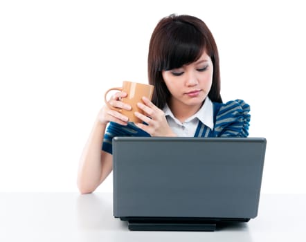 Portrait of a young Asian woman holding cup and looking at laptop over white background.