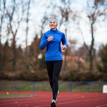 Young woman running at a track and field stadium