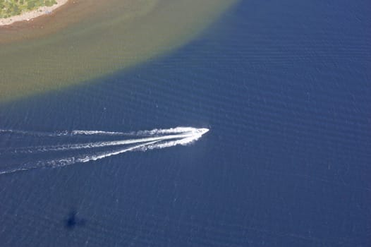 Small boat tracks on surface of water in sunlit
