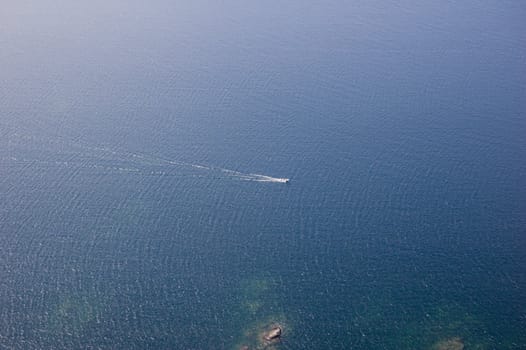 Small boat tracks on surface of water in sunlit