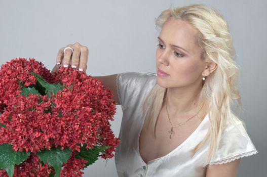 Portrait of a young beautiful girl with a bouquet of red flowers in vase