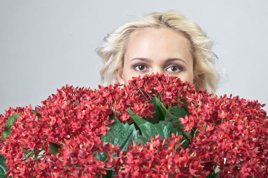 Portrait of a young beautiful girl with a bouquet of red flowers in vase