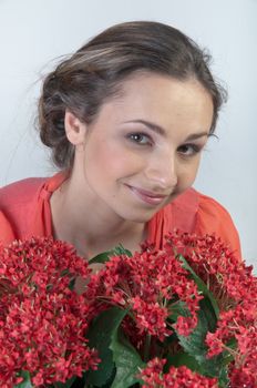 Portrait of a young beautiful girl with a bouquet of red flowers in vase