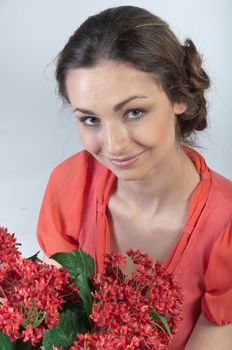 Portrait of a young beautiful girl with a bouquet of red flowers in vase
