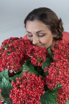 Portrait of a young beautiful girl with a bouquet of red flowers in vase