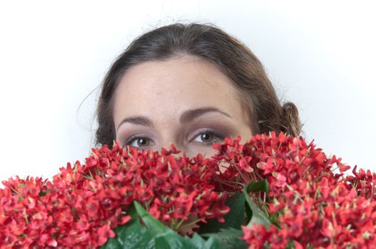 Portrait of a young beautiful girl with a bouquet of red flowers in vase