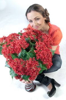 Portrait of a young beautiful girl with a bouquet of red flowers in vase