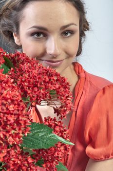 Portrait of a young beautiful girl with a bouquet of red flowers in vase