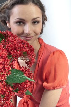 Portrait of a young beautiful girl with a bouquet of red flowers in vase