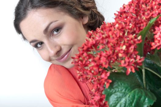 Portrait of a young beautiful girl with a bouquet of red flowers in vase