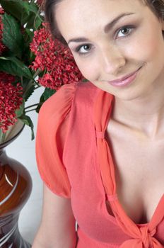 Portrait of a young beautiful girl with a bouquet of red flowers in vase