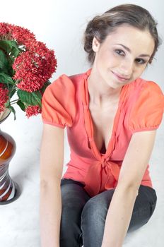 Portrait of a young beautiful girl with a bouquet of red flowers in vase