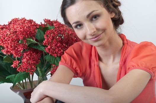 Portrait of a young beautiful girl with a bouquet of red flowers in vase