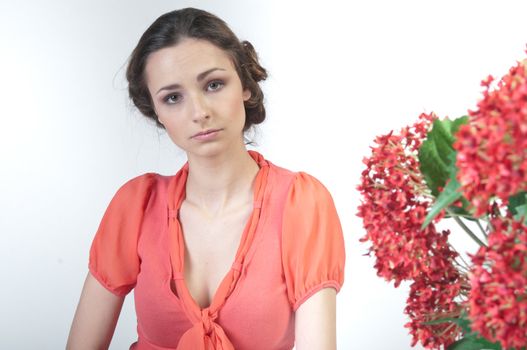 Portrait of a young beautiful girl with a bouquet of red flowers in vase