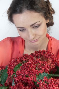 Portrait of a young beautiful girl with a bouquet of red flowers in vase