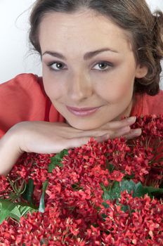 Portrait of a young beautiful girl with a bouquet of red flowers in vase