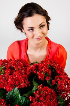 Portrait of a young beautiful girl with a bouquet of red flowers in vase