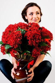 Portrait of a young beautiful girl with a bouquet of red flowers in vase