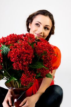 Portrait of a young beautiful girl with a bouquet of red flowers in vase