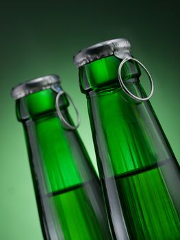 Two green bottles of beer on green background