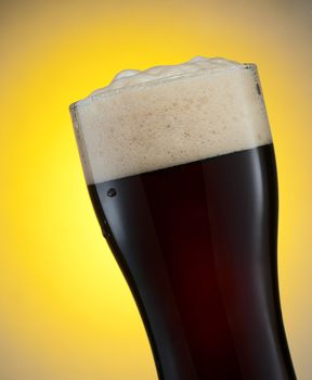 Glass of dark beer over yellow background