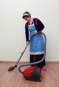 Housewife using a vacuum cleaner to clean the floor.