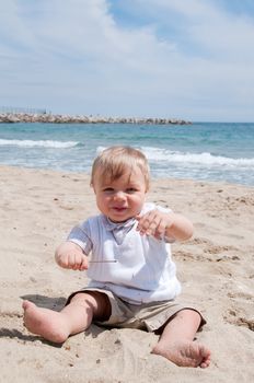 Happy little boy sitting on the beach