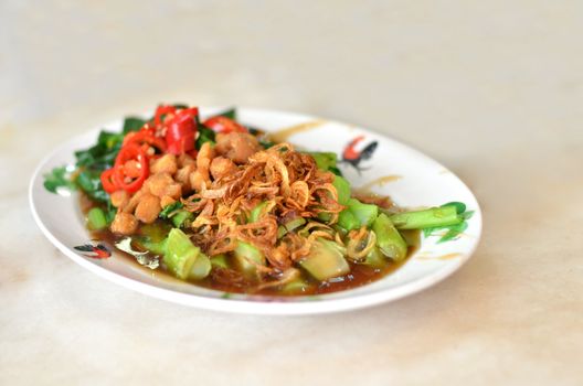 kale fried with oyster sauce  , topped with fried onion and red chili .