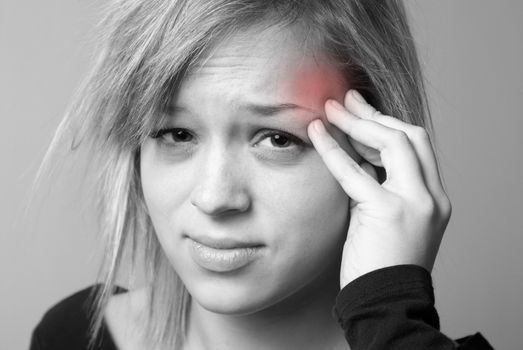 A young woman relieves the pain from her headache by putting pressure on her temple.