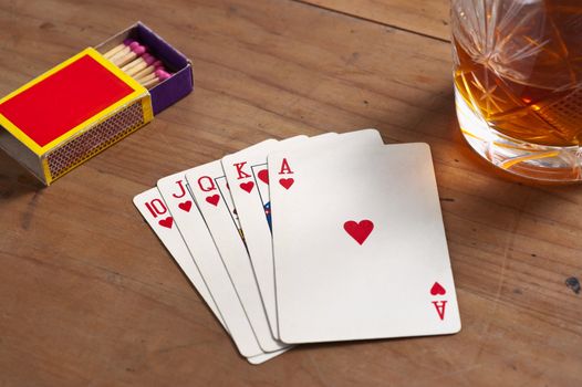 Poker cards and whisky glass on old wooden table. 