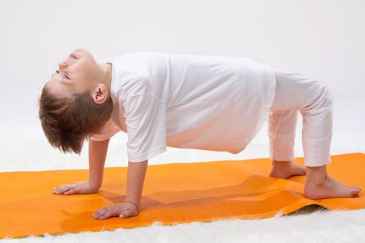 \Children's yoga. The little boy does exercise. 
