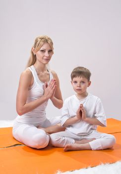 A beautiful young mother practices yoga with her son 