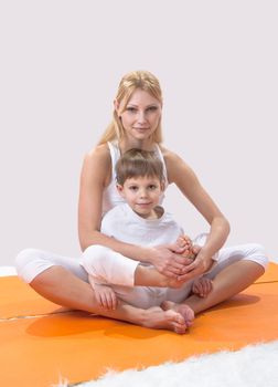 A beautiful young mother practices yoga with her son 