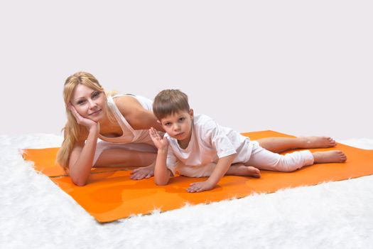 A beautiful young mother practices yoga with her son 