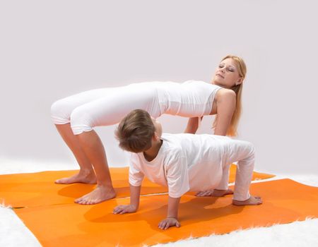 A beautiful young mother practices yoga with her son 