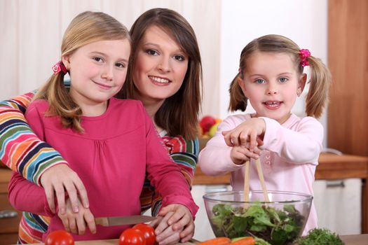 mother and her two girls making a salad